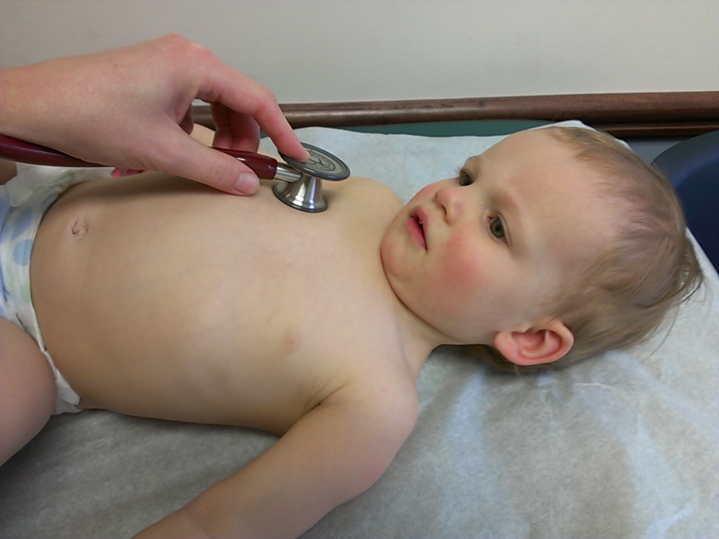 Clinician examining a child with a stethoscope during a physical exam